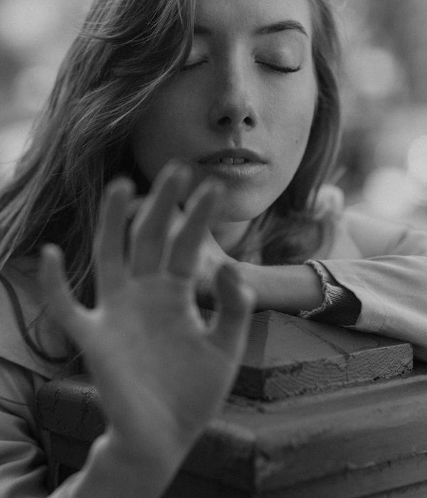 Woman in a dynamic yet calm pose against a dark background with amber light.